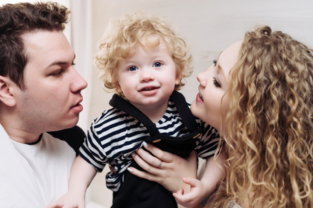 friendly young family, caring parents hold their little son, smileの写真素材