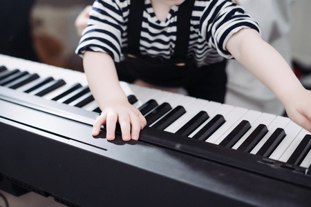 friendly family, little baby boy playing the piano, studying the worldの写真素材