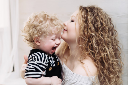 happy friendly family, curly mother holding her young son in her arms, laughingの写真素材