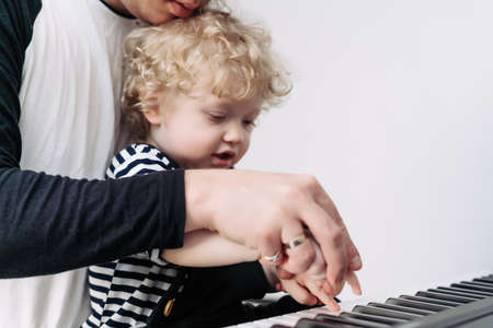 a young caring dad teaches his little son child to play the pianoの写真素材