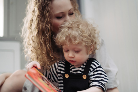 a friendly family, a curly, caring mother plays with her young child sonの写真素材
