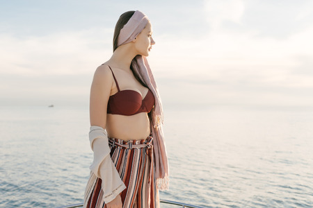 stylish young woman standing on her white yacht, enjoying the warmth and the seaの写真素材