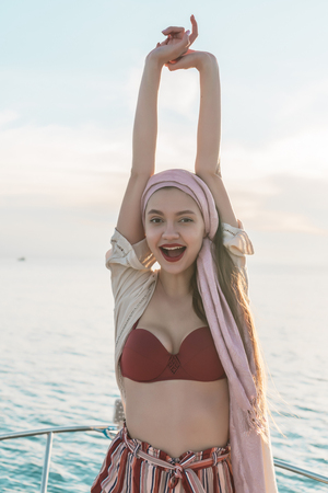happy stylish girl raised her hands up, rejoices long-awaited vacation and sea voyageの写真素材