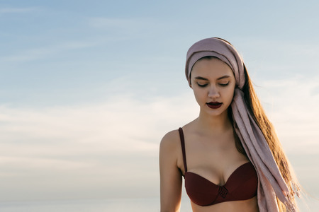 an attractive young girl with a headscarf on her head and in a bathing suit enjoying a sea voyage and a vacationの写真素材