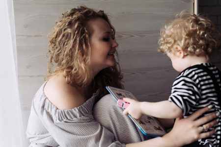 kind young mother plays with her young son, smiles, amicable gay familyの写真素材