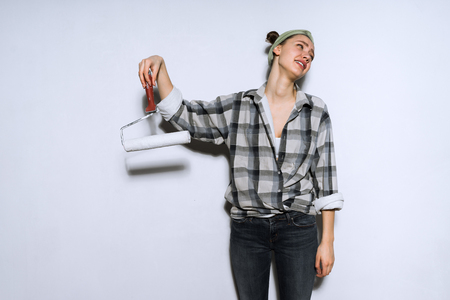 young girl tired of doing repairs, holds roller for painting wallsの写真素材