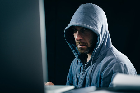 criminal bearded man hides his face under the hood, does something illegalの写真素材