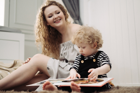 a friendly and cheerful family, a curly young mother sits next to her little son, spend time togetherの写真素材