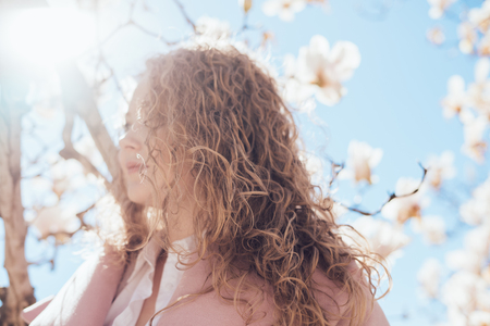 cute curly young woman enjoying spring heat in the park in the sunの写真素材