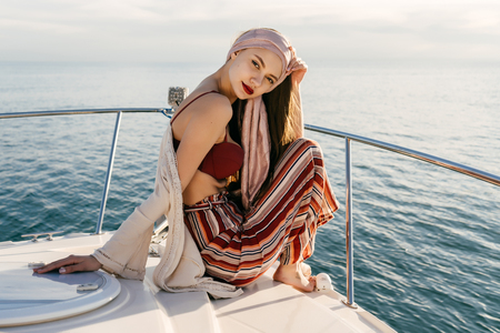 confident stylish girl in summer clothes sits on a ship and looks at the camera, sails on the Caribbean seaの写真素材