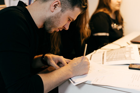 serious young man in black sweater working on project in office