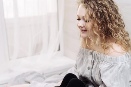 beautiful curly young woman resting and relaxing at home, good mood, smilingの写真素材