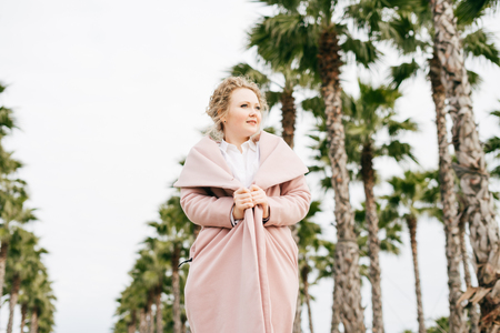 stylish young woman walks along the green park next to tall palms, loves the springの写真素材
