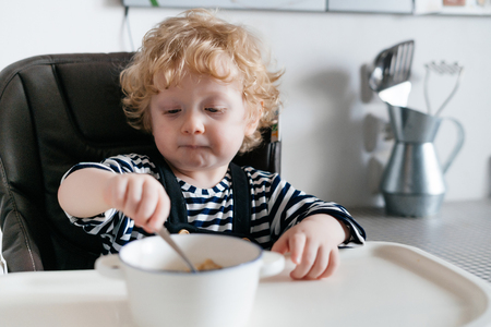small independent child the boy eats a delicious useful cereal for breakfastの写真素材