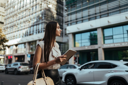 Young business lady catches a taxi at workの写真素材