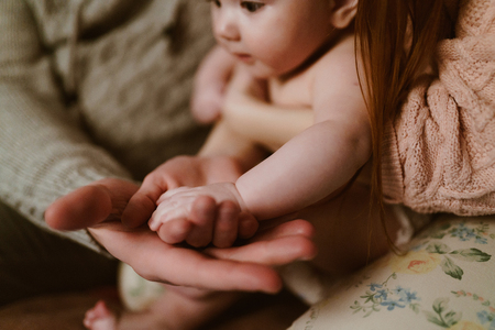 Father's big hand holds a small pen of a newborn sonの写真素材