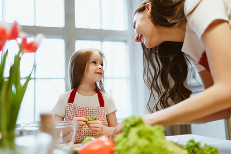 Mom and daughter cook together, look at each other and smile, mother's dayの写真素材