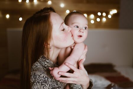 Young mother kisses her child, gently covering her eyesの写真素材