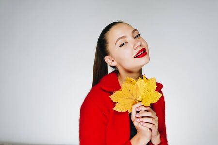Gorgeous young girl with long dark hair tied in a ponytail with a black sweater with a red jacket on...
