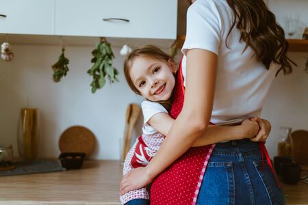 daughter hugs mom at the waist in the kitchenの写真素材