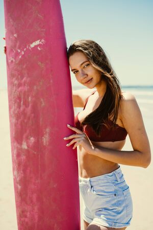 girl on the beach leaned on a surfboard