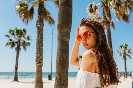 girl on the beach looks around on the background of the tops of palm treesの写真素材