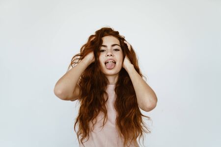 schoolgirl covered her ears with her hands and shows tongue