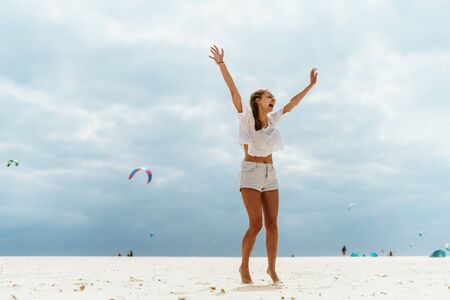 girl runs along the beach, arms outstretched against a background of skitesの写真素材