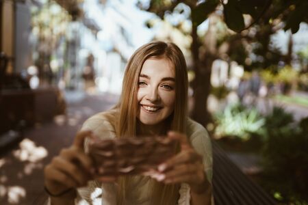 girl in the sun with a smile takes photos on the phoneの写真素材
