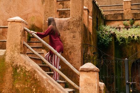 a girl in Asian clothes with loose hair rises up the stairs of the old cityの写真素材