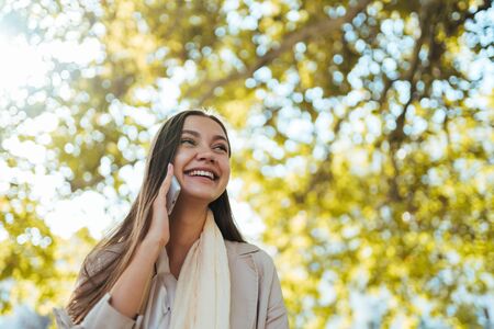 uncontrollable joy on the face of a girl holding a phone by her ear. around golden autumnの写真素材