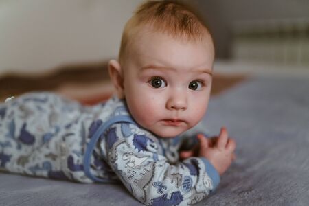 the baby lies on his tummy and looks at the camera curiouslyの写真素材