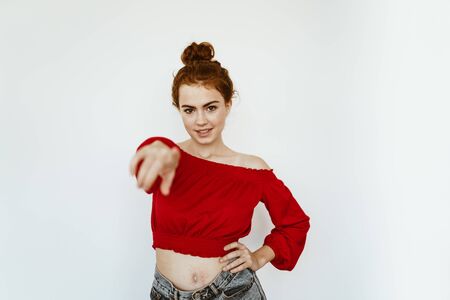 beautiful girl with a smile pointing her finger at the camera. gray backgroundの写真素材