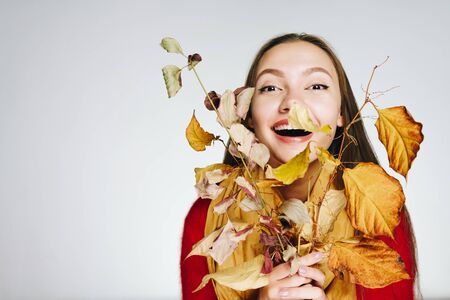 a girl with autumn branches presses them to herself and laughs joyfullyの写真素材