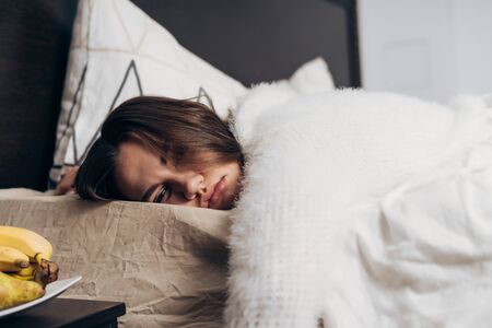 the girl fell asleep in bed right in clothes lying on her stomach, on the nightstand next to fruitの写真素材