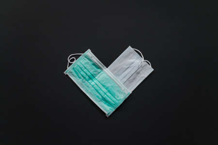 A symbol of the heart made of medical masks on a black background. Pandemic and epidemic, Valentines Day. High quality photoの写真素材