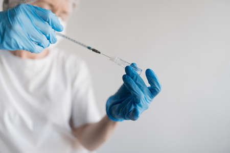 Doctor dials vaccine in syringe on white background. High quality photo