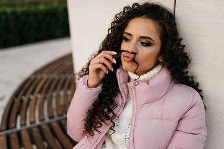 A woman with curly dark long hair playfully put one strand under her nose imitating a mustache. High...