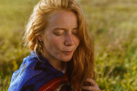 Against the background of steppe grass a girl with lowered eyes of natural beauty without makeup in...