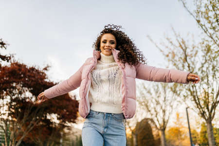 Girl with fluttering hair runs through the park with her arms outstretched to the sides. High...