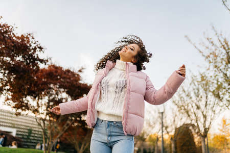 Gleefully smiling nonchalantly throws up her hair with her head over and dances in the park a girl in warm clothes. High quality photoの写真素材