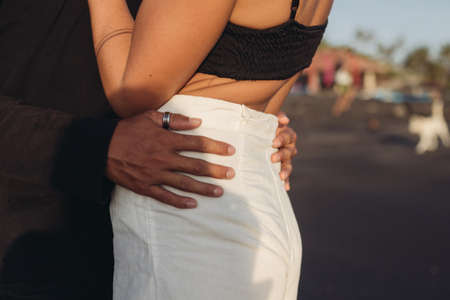Pictured, a mans arms hug a woman in a white skirt at the waist. High quality photoの写真素材