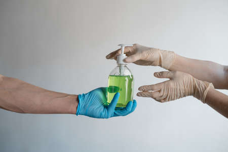 Mens and womens hands give each other liquid soap on a white background. High quality photoの写真素材