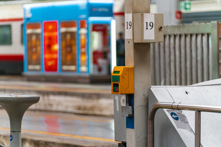 4.10.2021 Milan, Italy - Milano Centrale railway station. A device for validating train tickets hangs on a pole near the platform. composter for tickets, travel in Europe, equipment at the railway stationの写真素材
