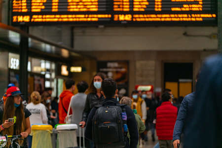 4.10.2021 Milan, Italy - Milano Centrale railway station. Travelers with luggage and backpacks stand...