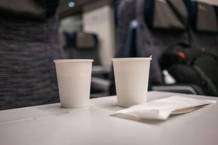 White paper disposable cup with coffee and wooden stick on the table on the train. High quality photoの写真素材
