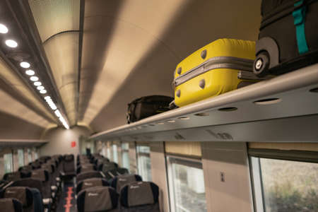 Suitcases lying in the cabin of the train in places for the handle luggage. Travelling in Europe by train, euro-trek, luggage rack. High quality photoの写真素材