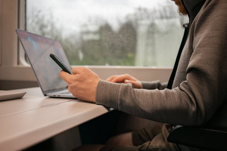 A male traveler works online on a European train while traveling by train. Unrecognizable man. High quality photoの写真素材