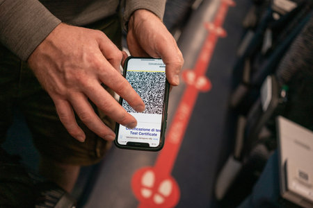 A mans hand shows off a phone screen with a QR code of a vaccination certificate during a check on a...