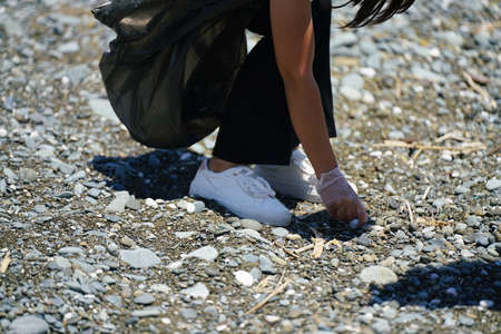 womans hand collects garbage on the beach with gloves. High quality photo